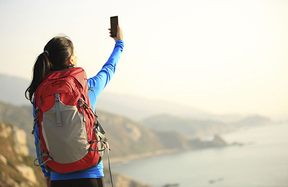 Why Hotel Marketers Must Think "Backyard and Bundle" When Demand Returns: Guest taking a selfie while hiking