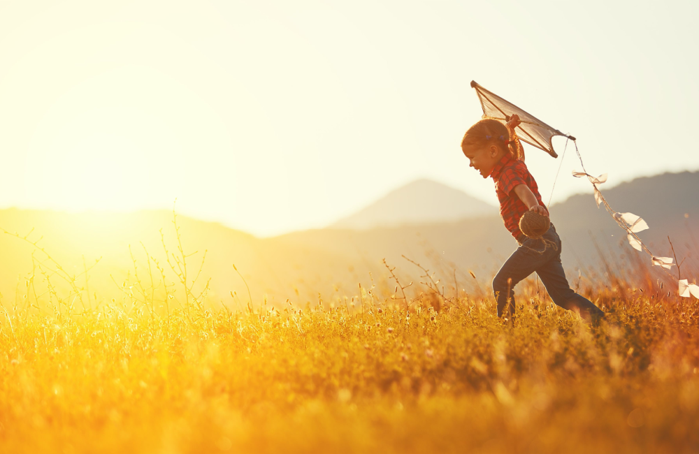 Happy child launching a kite in glowing sunshine to illustrate the concept of how you get to make it better