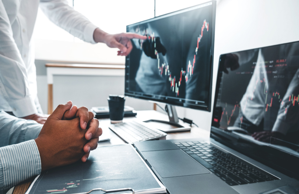 Two men looking at graph of stock prices on computer monitor to illustrate Big Tech (the AGFAM's) earnings season