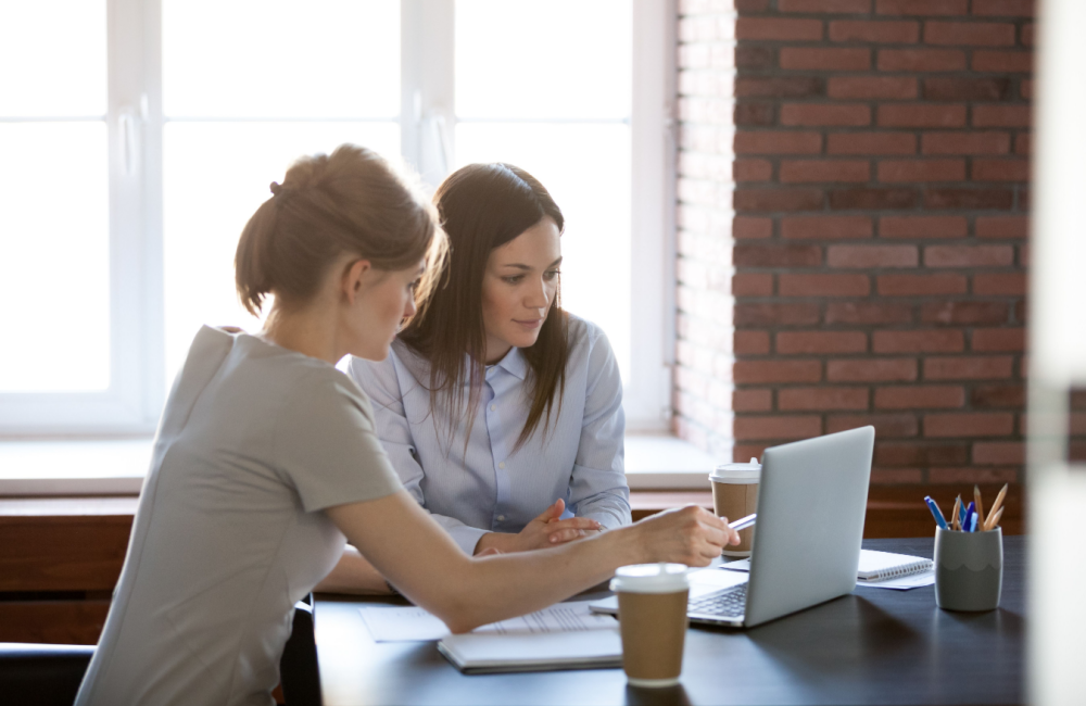 Two women sharing ideas at a laptop to highlight the question "Will AI and ChatGPT kill your search traffic?"